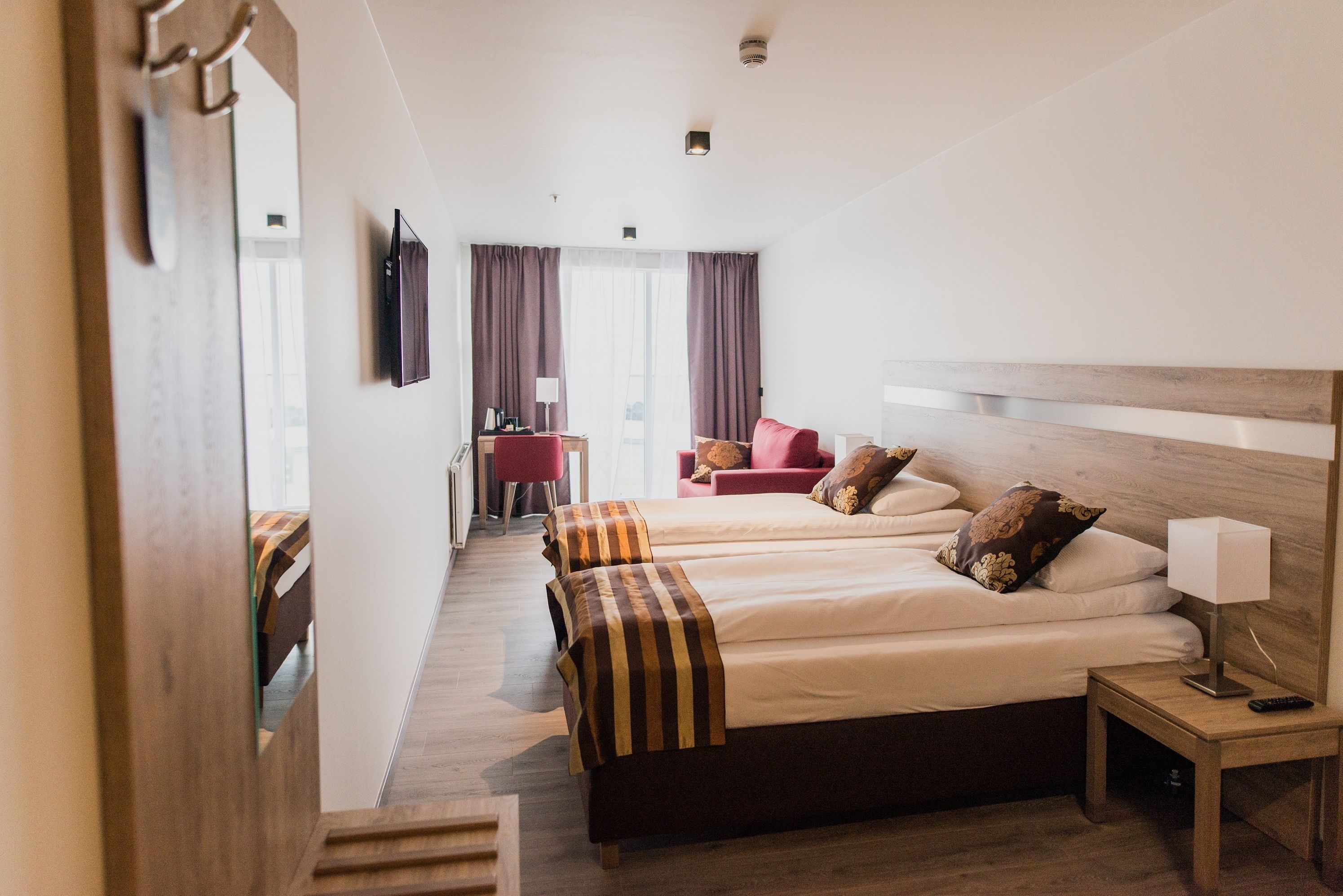 Una habitación de hotel con dos camas, un escritorio, una silla y un televisor.