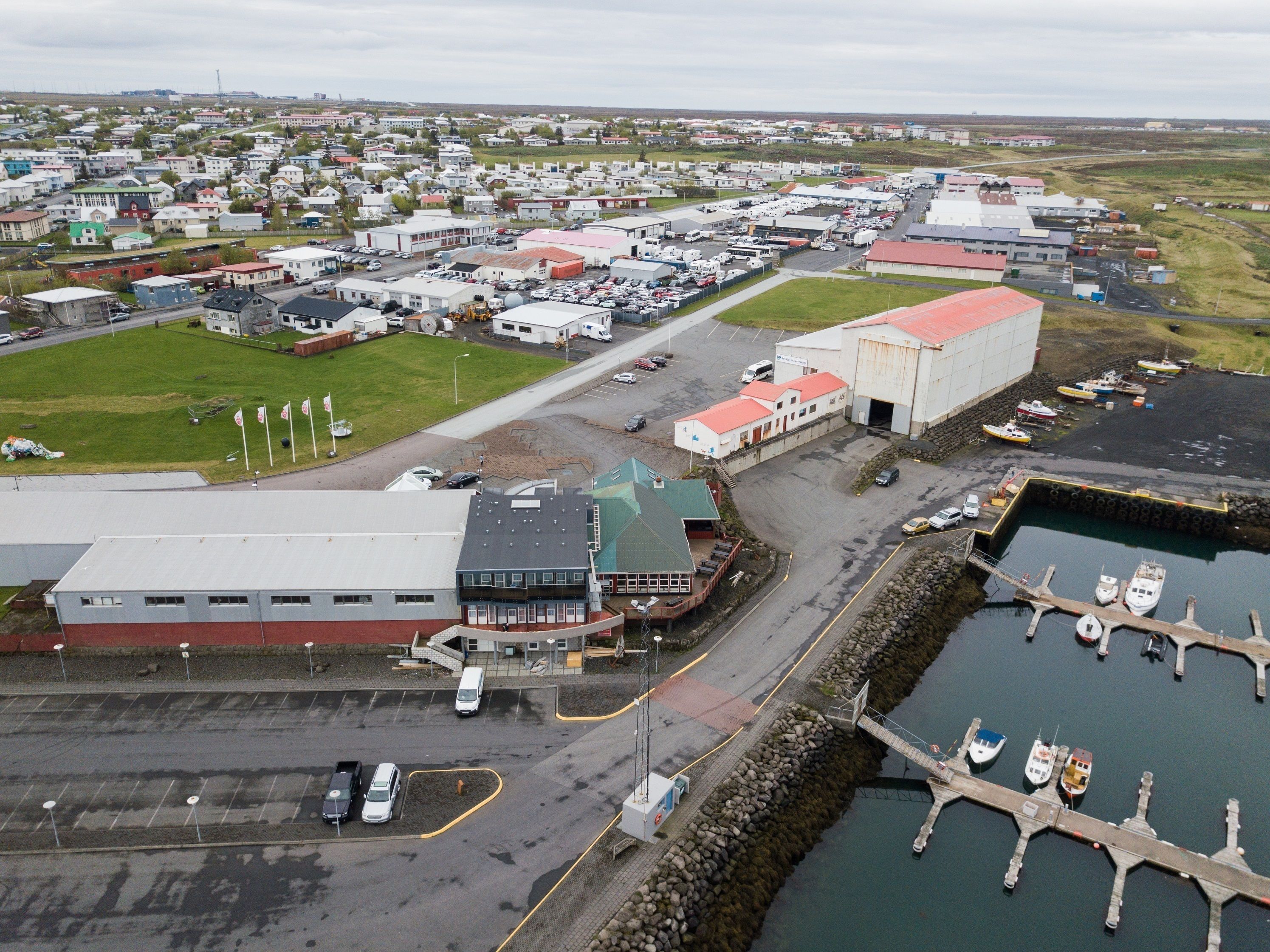 An aerial view of a coastal town with a marina, industrial buildings, and residential areas.