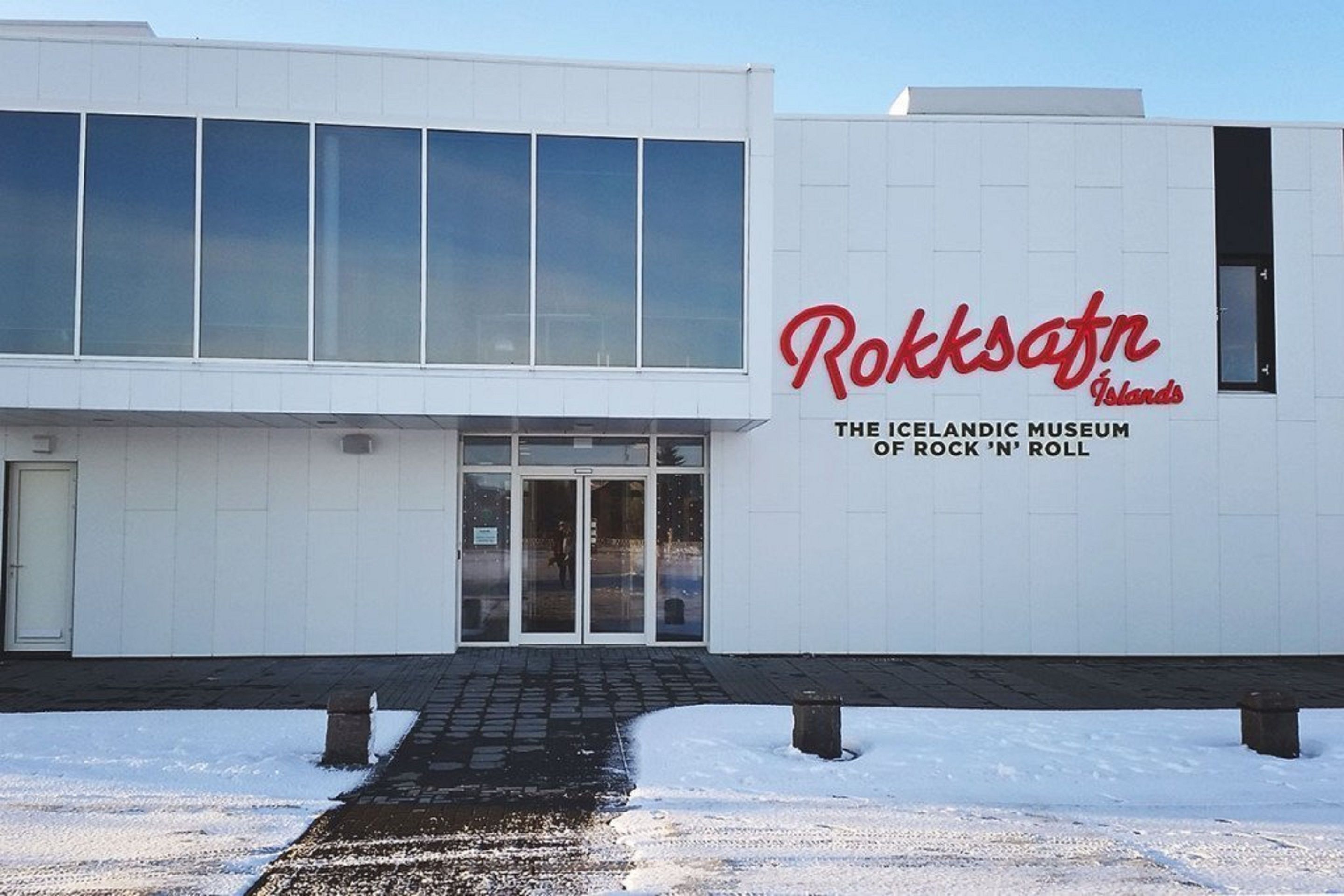 A building with a large glass facade and a sign reading "Rokkafn Islands The Icelandic Museum of Rock 'n' Roll".