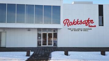A building with a large glass facade and a sign reading "Rokkafn Islands The Icelandic Museum of Rock 'n' Roll".