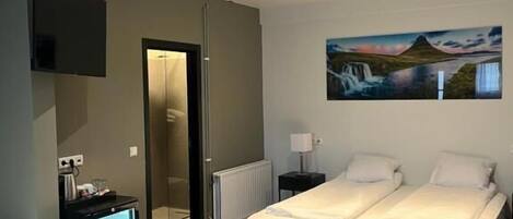 A modern hotel room with a large bed, a bedside table, a TV, and a painting on the wall.