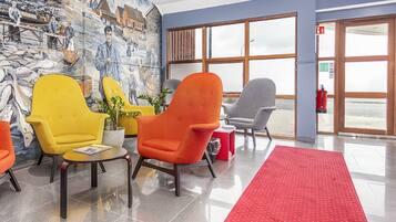 A lobby with colorful chairs, a red carpet, and a mural of workers on a dock.