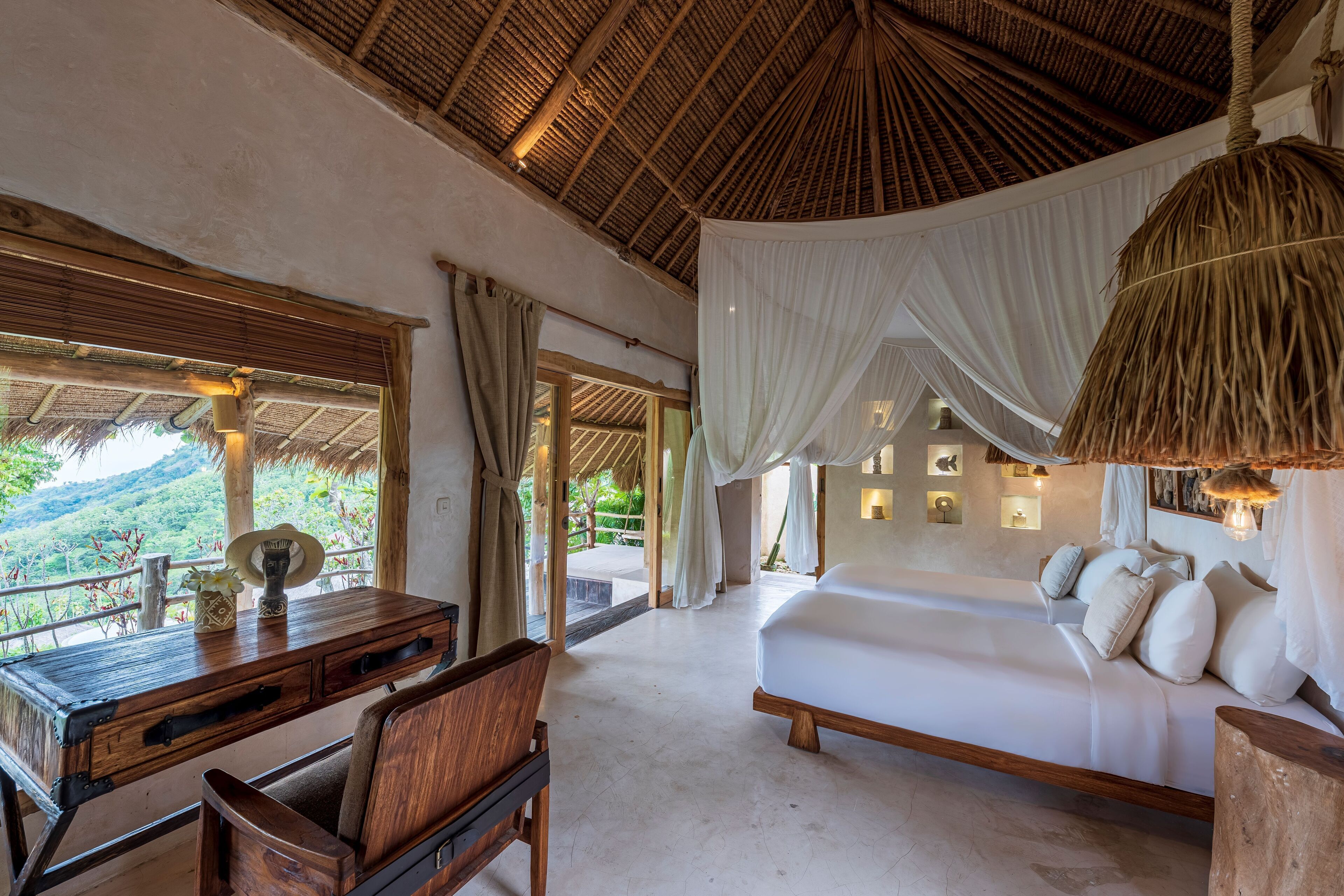 A bedroom with a large bed, wooden furniture, and a view of the outdoors.