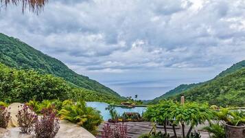 A tropical resort with a pool, lush greenery, and a mountainous backdrop.