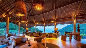 An open-air lounge with thatched roof, comfortable seating, and a chessboard.