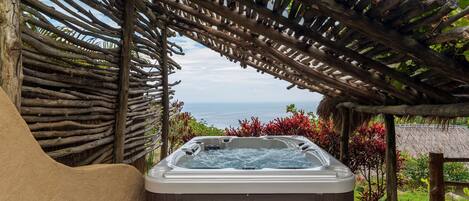 Ein Whirlpool unter einer Hollaube mit Blick auf das Meer.