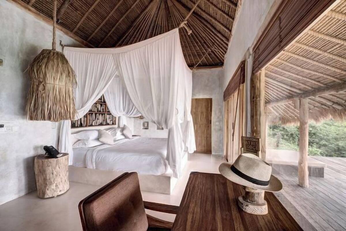 Une chambre à coucher avec un lit à baldaquin, une table en bois, un chapeau et un mur rustique.