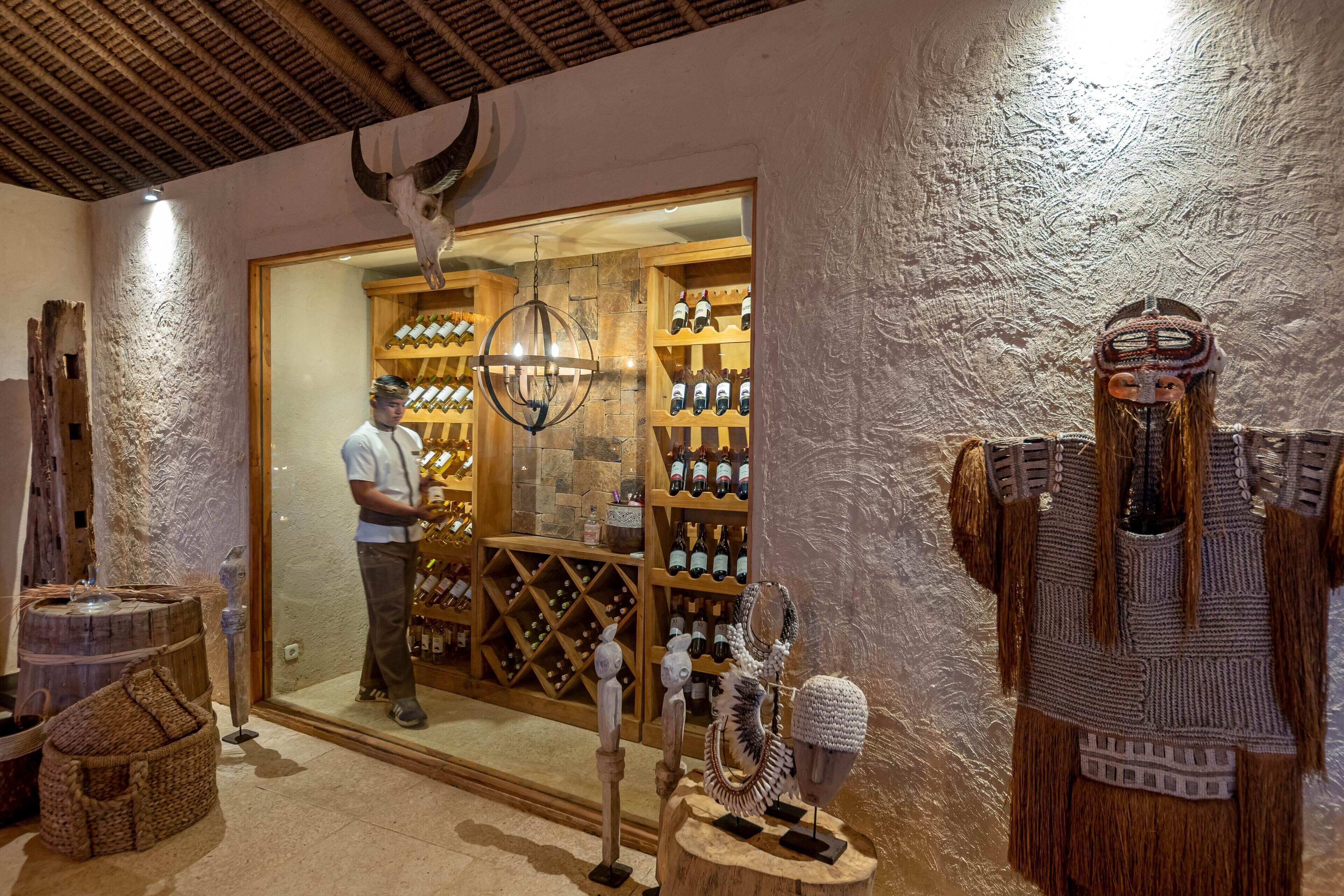 Una habitación con techo de madera, una estantería para vinos y una exhibición de botellas.
