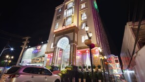 Un hôtel à plusieurs étages, doté d’une entrée imposante, d’une enseigne lumineuse et d’une façade bien éclairée.