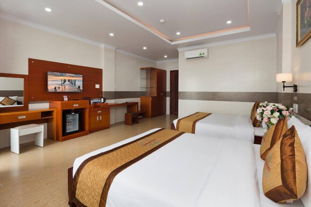 Habitación de hotel con dos camas, un escritorio, un minibar y un cuadro grande en la pared.