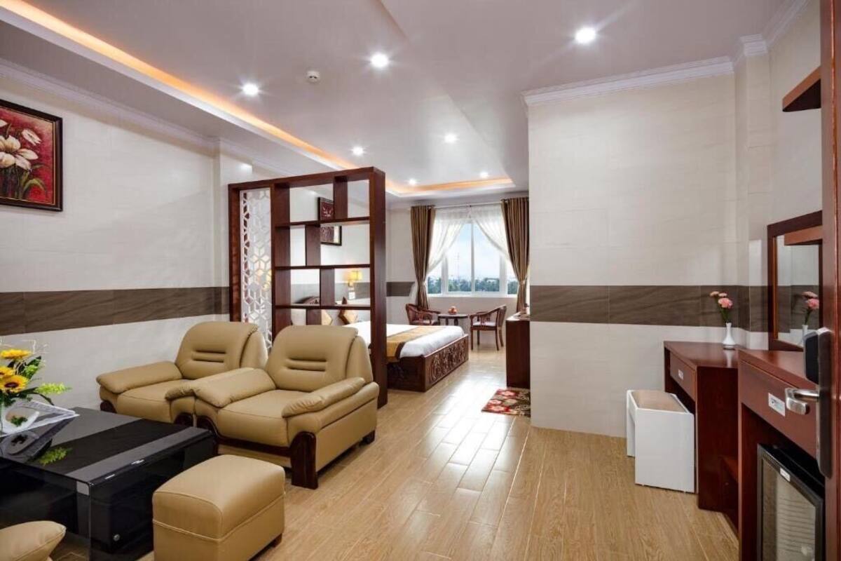 Habitación de hotel con sofá, mesita, cama, escritorio y espejo.