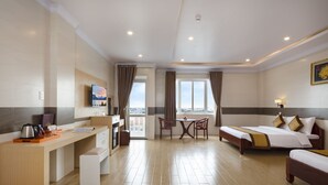 Une chambre d’hôtel comprenant un lit, un bureau, une chaise, une petite table et un balcon avec des rideaux.