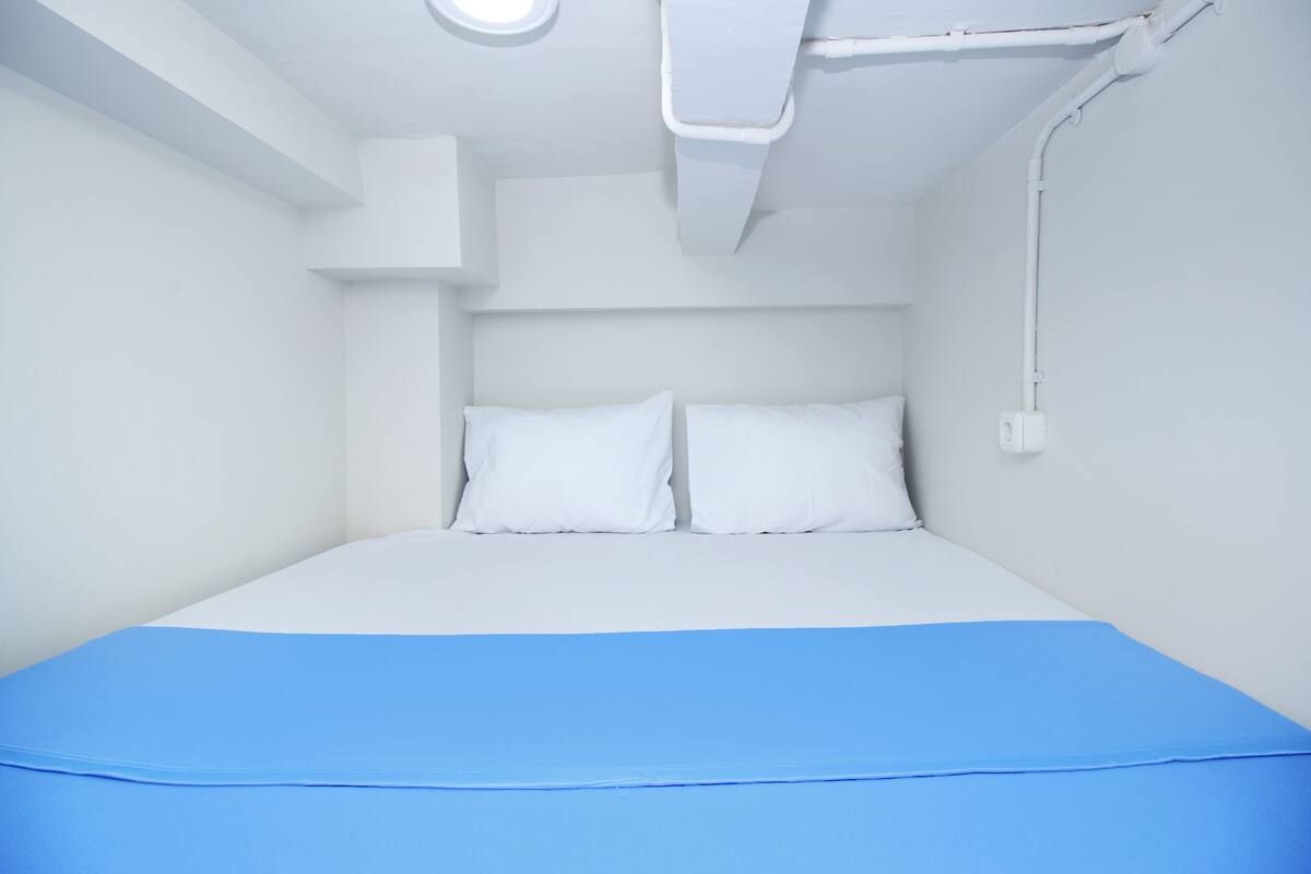 A room with a bed, white walls, and a blue bedspread.