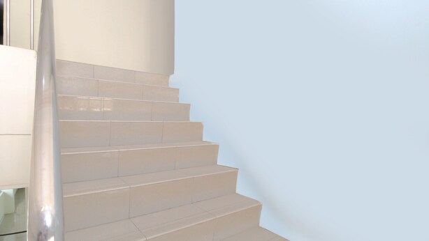 Una escalera con barandilla y una pared de color claro.