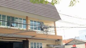 Un edificio de varios pisos con techo de tejas, un garaje y varios coches aparcados.