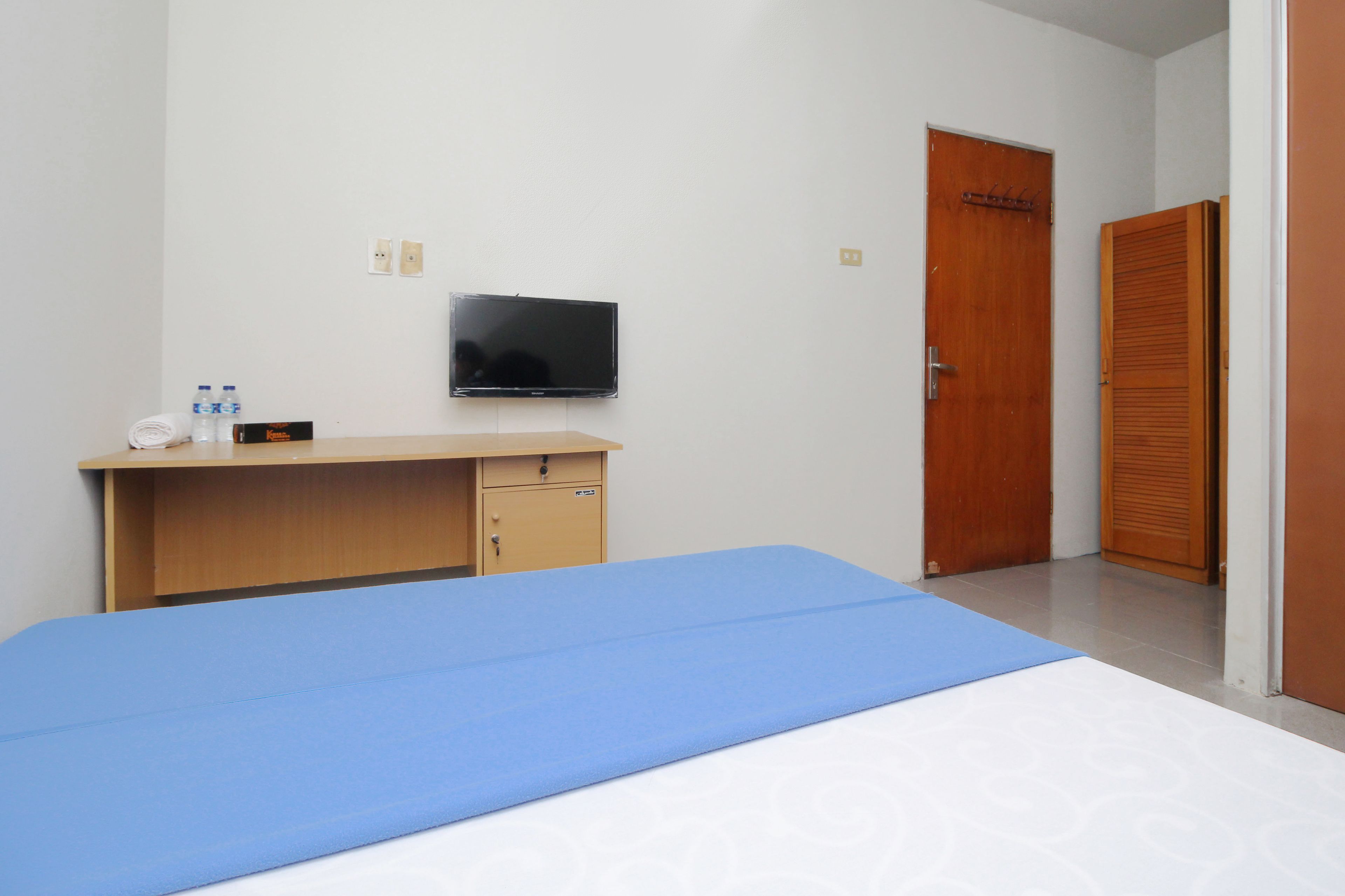 A room with a bed, a desk, a television, and a wardrobe.