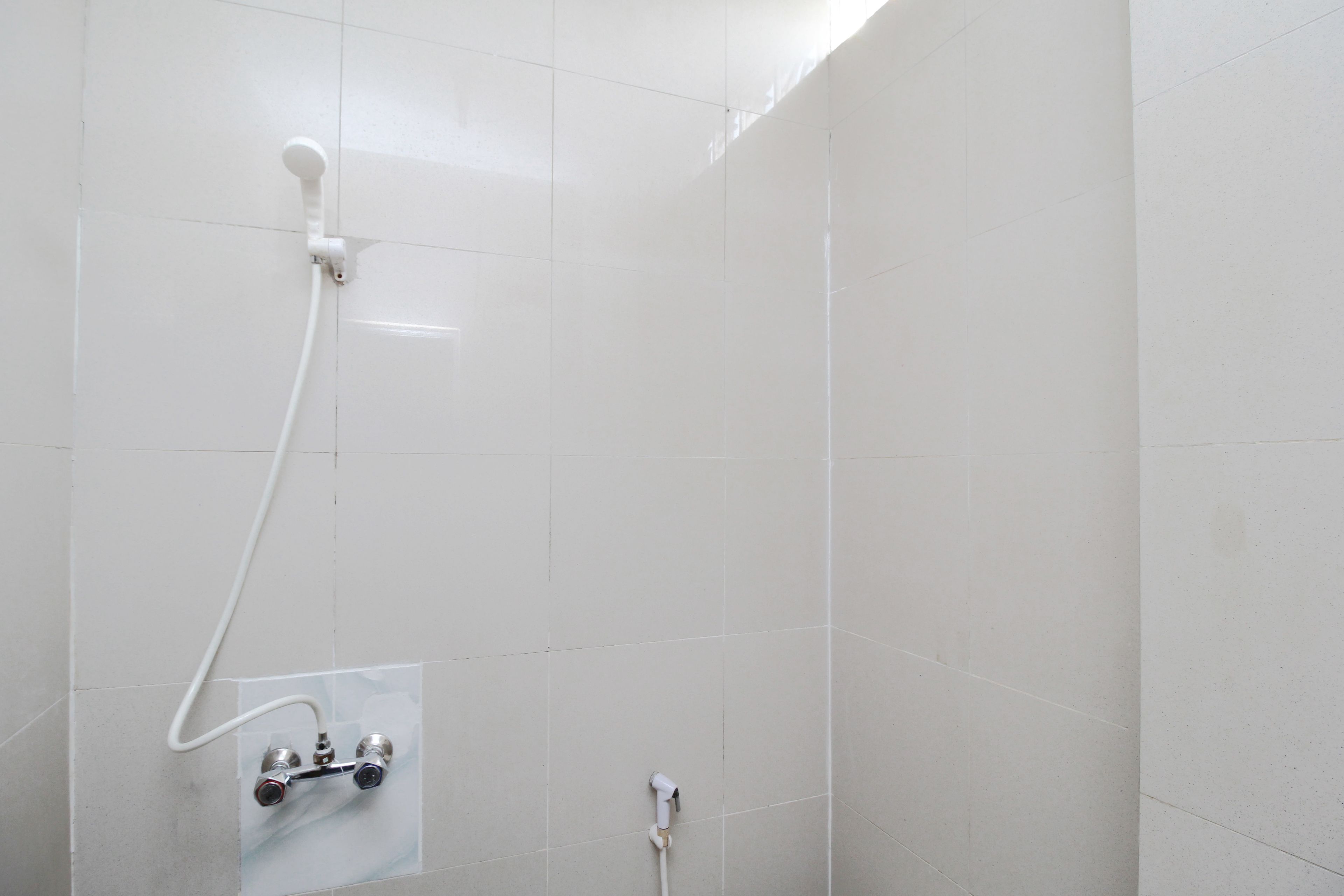 A shower area with white tiles and a visible showerhead.