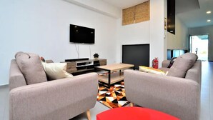Una sala de estar moderna con un televisor de pantalla plana montado en la pared, un sofá, una mesa de centro y una alfombra estampada.