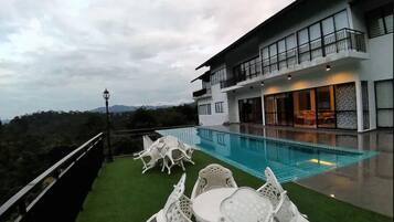 A modern house with a swimming pool, a balcony, and outdoor furniture.