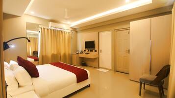 A hotel room with a bed, a desk, a chair, a TV, and a wardrobe.