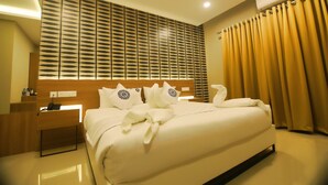 A hotel room with a large bed, a wooden headboard, a nightstand with a phone, and a wall-mounted air conditioner. - Noorjehans Grand Noor (Palakkad)