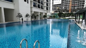 Una piscina con agua azul cristalina, rodeada por un edificio blanco con balcones.