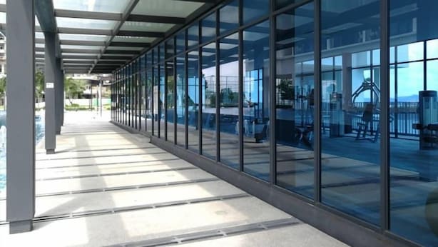 Un pasillo cubierto con paredes de vidrio que conduce a una zona de piscina.