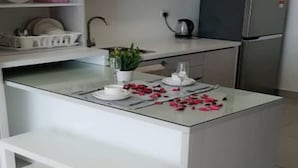 Una cocina moderna con armarios blancos, una isla central con banco y un refrigerador.