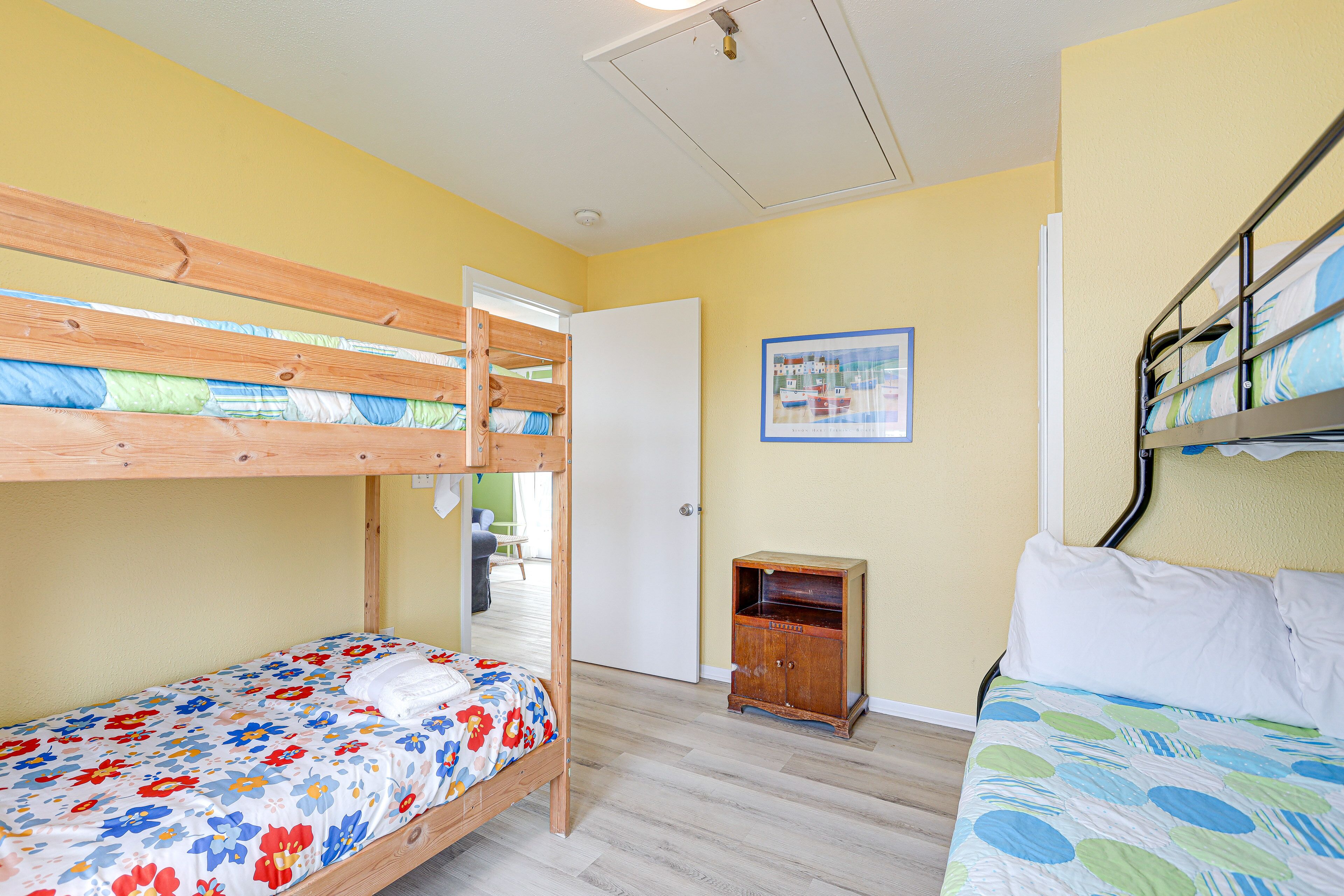 Quarto com duas beliches, um armário de madeira e uma porta que dá para outro cômodo.