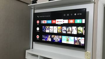Un televisor de pantalla plana montado en una pared blanca con un estante encima.
