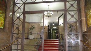 A grand entrance with a glass door, a staircase with red steps, and a chandelier. - Apartment in Copacabana, 4 bedrooms, 3 bathrooms, 50 meters from the beach, shops, and supermarket. (Rio de Janeiro)