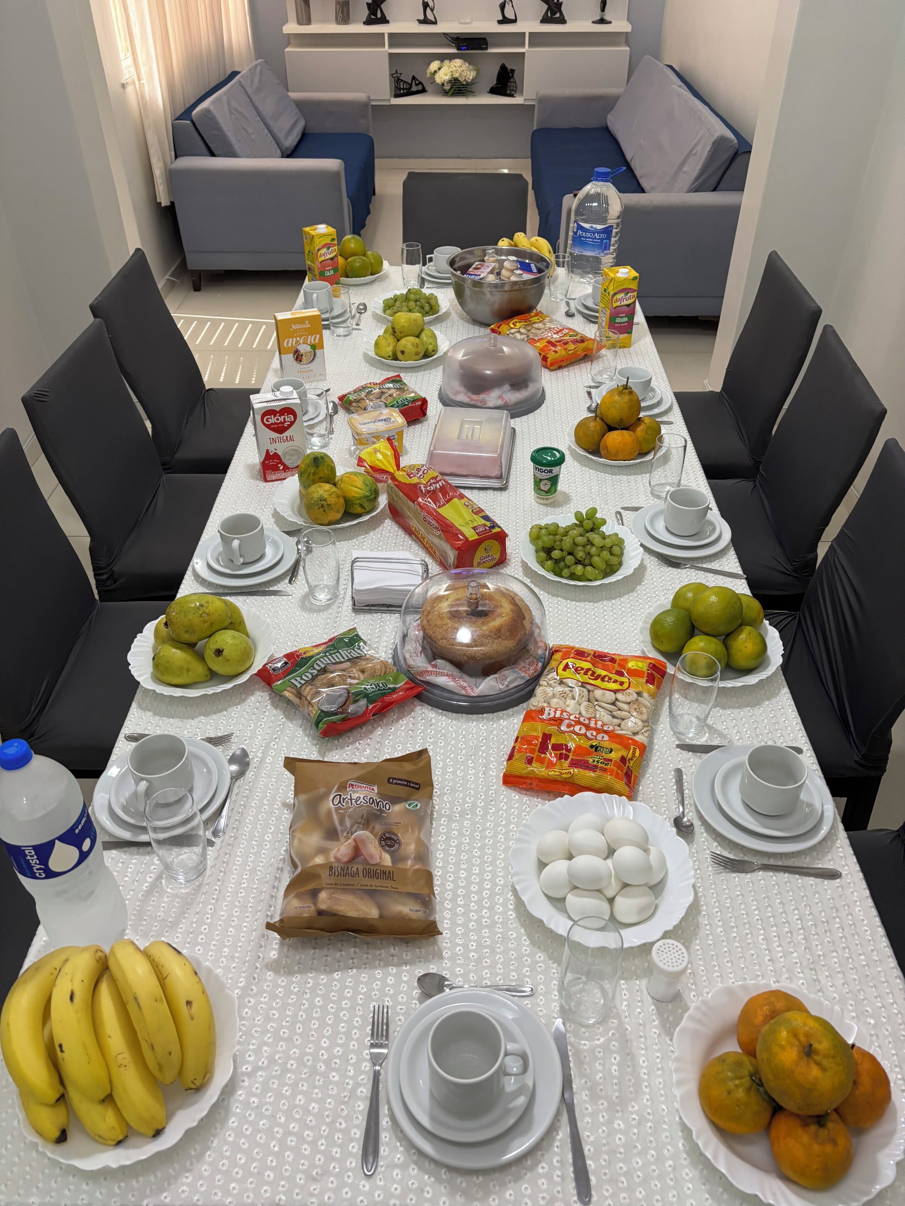 A dining table set with various food items and utensils, surrounded by black chairs.