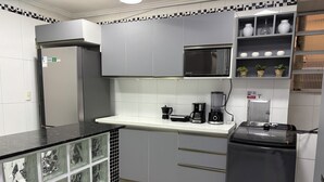 A kitchen with grey cabinets, a black refrigerator, a microwave, a coffee maker, and a blender. - Apartment in Copacabana, 4 bedrooms, 3 bathrooms, 50 meters from the beach, shops, and supermarket. (Rio de Janeiro)