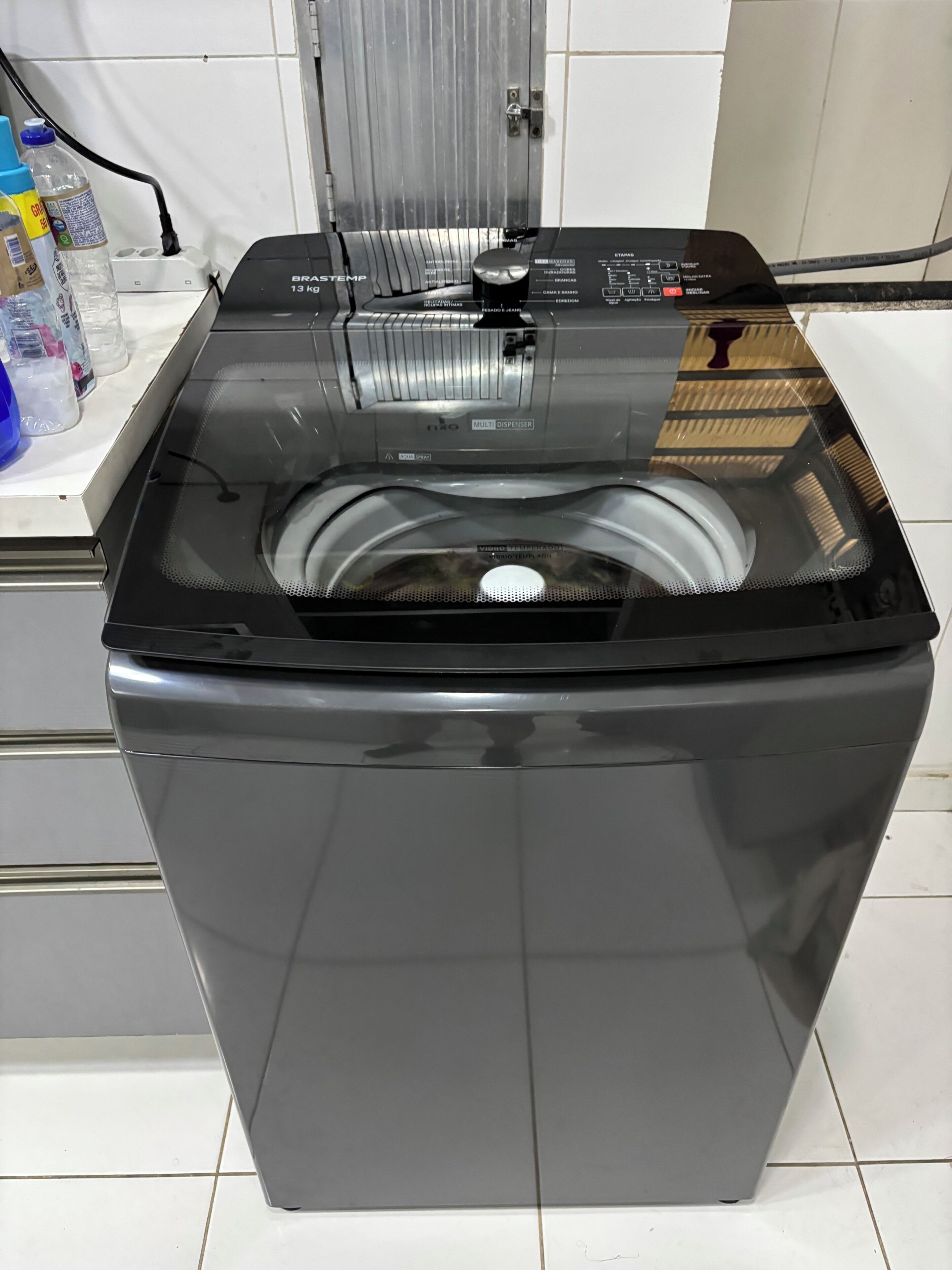 A front view of a modern, stainless steel front-loading washer and dryer unit with a control panel and a water inlets on the top.
