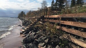 A wooden boardwalk along a rocky shoreline with a view of the sea and trees in the background. - Simple Gifts - A Simple Studio Cabin with Lake Sup (La Pointe)
