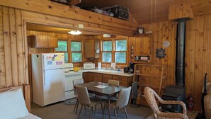 Un interior de cabaña con comedor, cocina y chimenea.