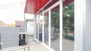 Un edificio con ventanas amplias y un toldo rojo. Se observa un cartel de accesibilidad para sillas de ruedas.