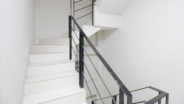 Una escalera con peldaños blancos y barandales de metal negro.