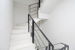 A staircase with white steps and black metal railings. - Kamar Keluarga Kemanggisan Syariah (Jakarta)