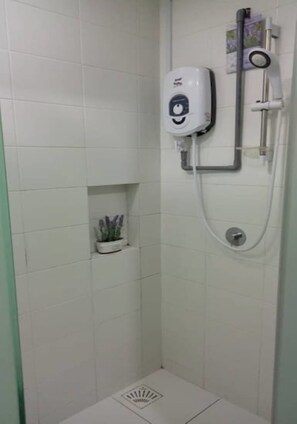 A shower with a handheld spray head and a wall-mounted faucet.
