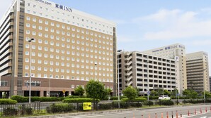 A multi-story hotel with a prominent sign, a parking garage, and a clear sky. - Toyoko Inn Chubu International Airport No.2 (Tokoname)