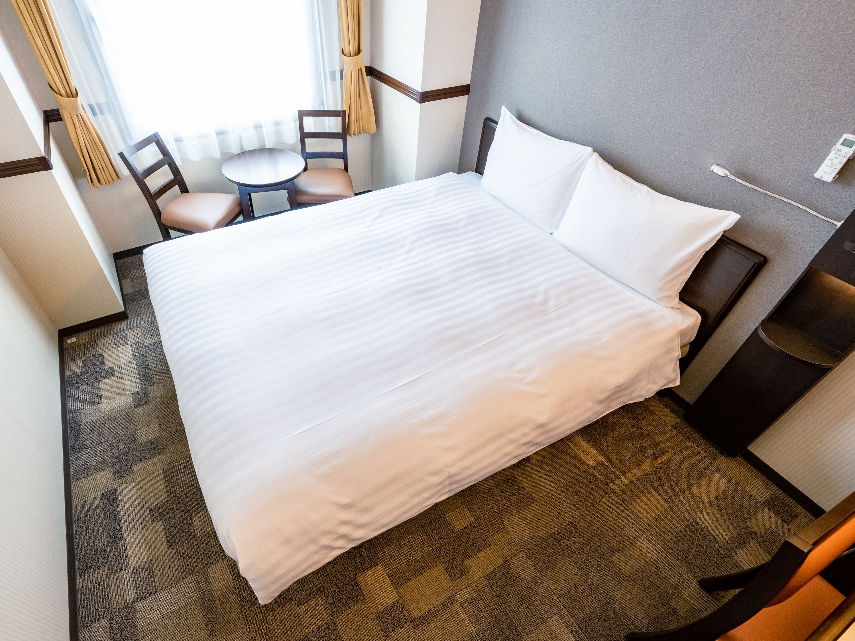 Une chambre d’hôtel avec un grand lit, une petite table, deux chaises et une table de chevet avec une lampe.