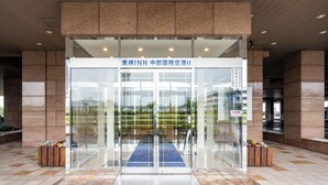 A modern building entrance with glass doors, a blue carpet, and stone flooring. - Toyoko Inn Chubu International Airport No.2 (Tokoname)