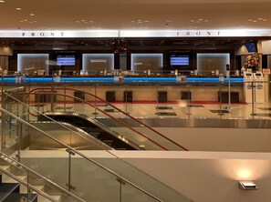 Un moderno vestíbulo de hotel con un mostrador de recepción, pantallas informativas digitales y una escalera de cristal.