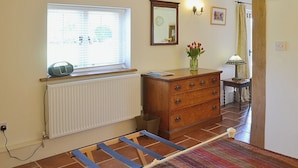 A room with a radiator, wooden dresser, and a window with blinds.