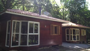 Una piccola casa in legno a un solo piano con tetto rosso, ampie finestre e un'antenna parabolica.