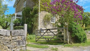 A stone house with ivy and purple flowers, a wooden gate, and a stone wall. - 3 bedroom accommodation in Church Enstone, near Chipping Norton (Church Enstone, near Chipping Norton)