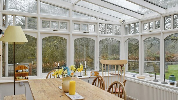 A conservatory with a wooden table, chairs, a lamp, and a vase with flowers. - 3 bedroom accommodation in Church Enstone, near Chipping Norton (Church Enstone, near Chipping Norton)