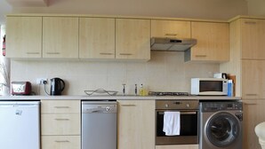 Una cocina compacta equipada con lavavajillas, estufa, microondas y lavadora.