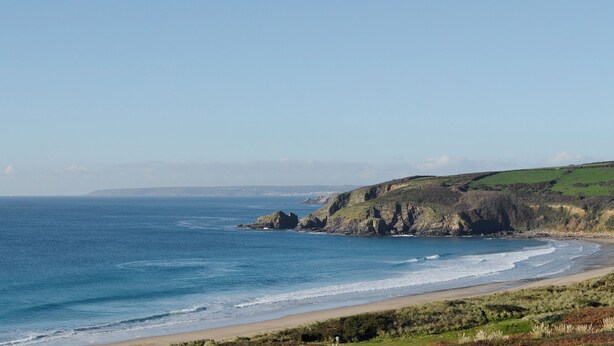 Eine Küstenlandschaft mit Strand, Klippen und blauem Himmel.